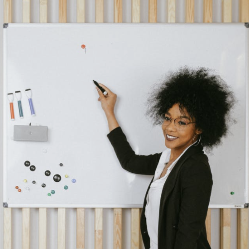 a woman writing on a whiteboard